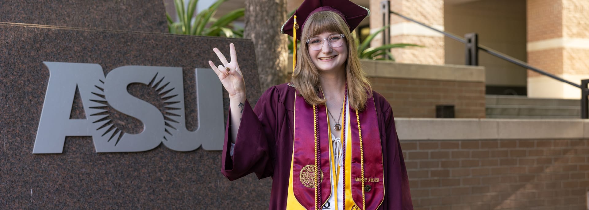 ASU student in graduation regalia smiling